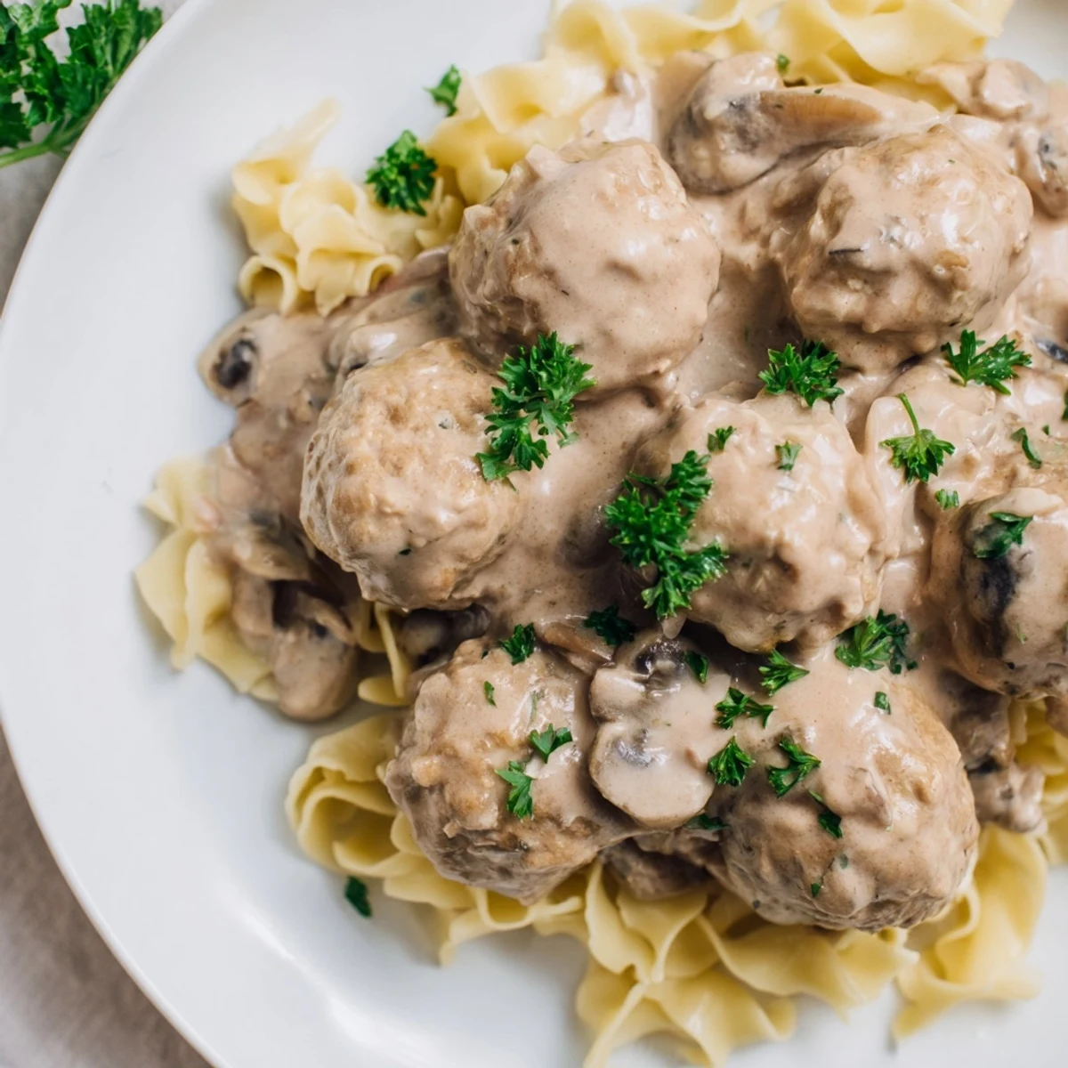 A close view of savory turkey meatballs in rich stroganoff sauce, garnished with fresh parsley beside a fork.