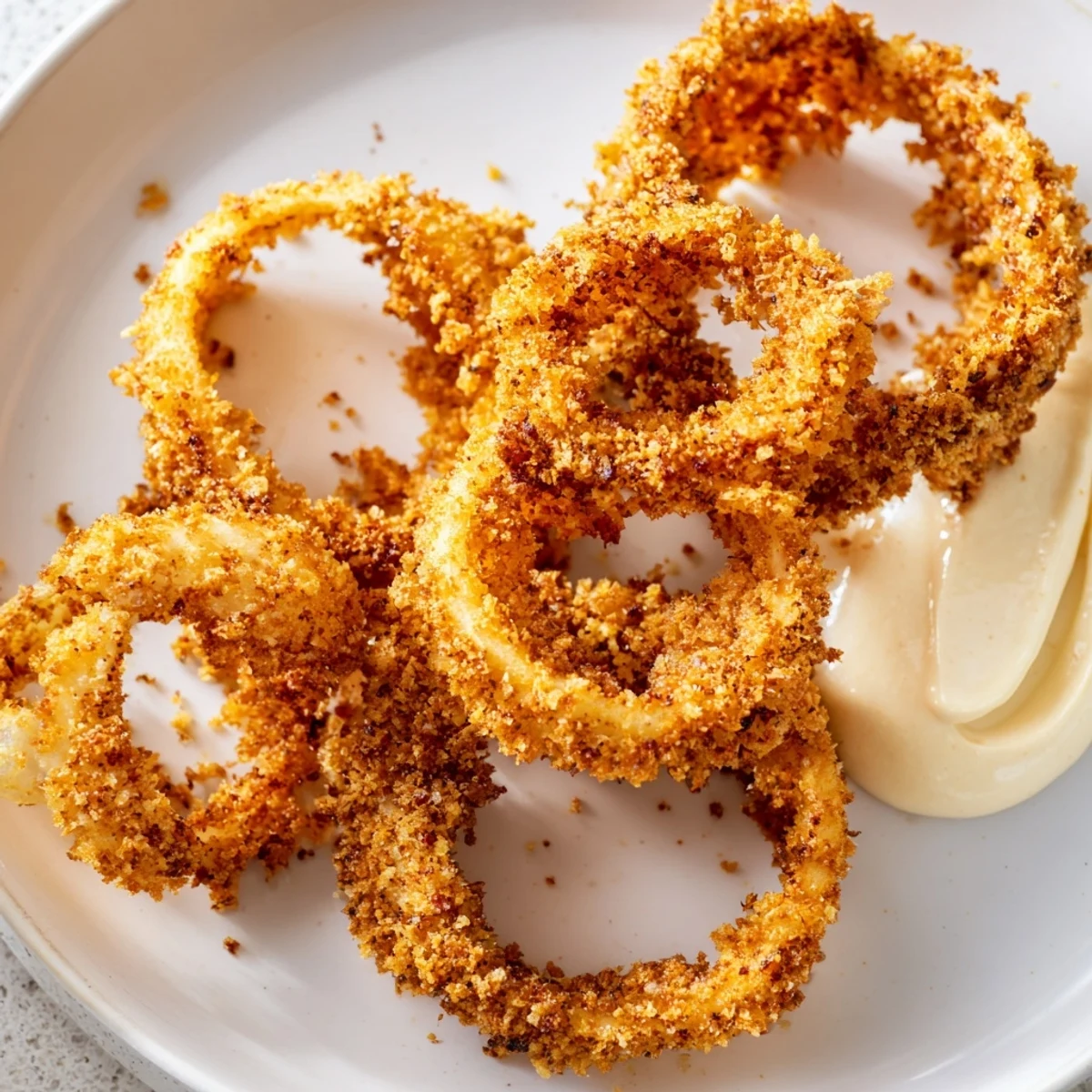 Golden, crispy Air Fryer Onion Rings with Chipotle Mayo on a plate, perfect for dipping.