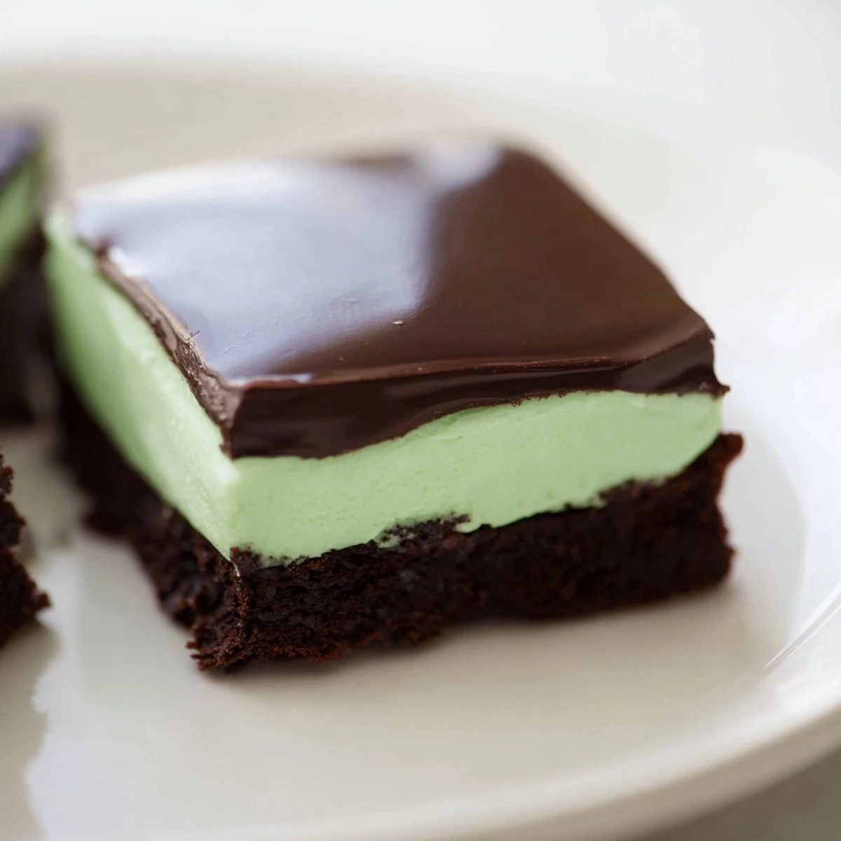 A close-up of Shamrock Mint Brownies with Chocolate Ganache, showing fudgy squares topped with glossy ganache and a vibrant green mint layer.  