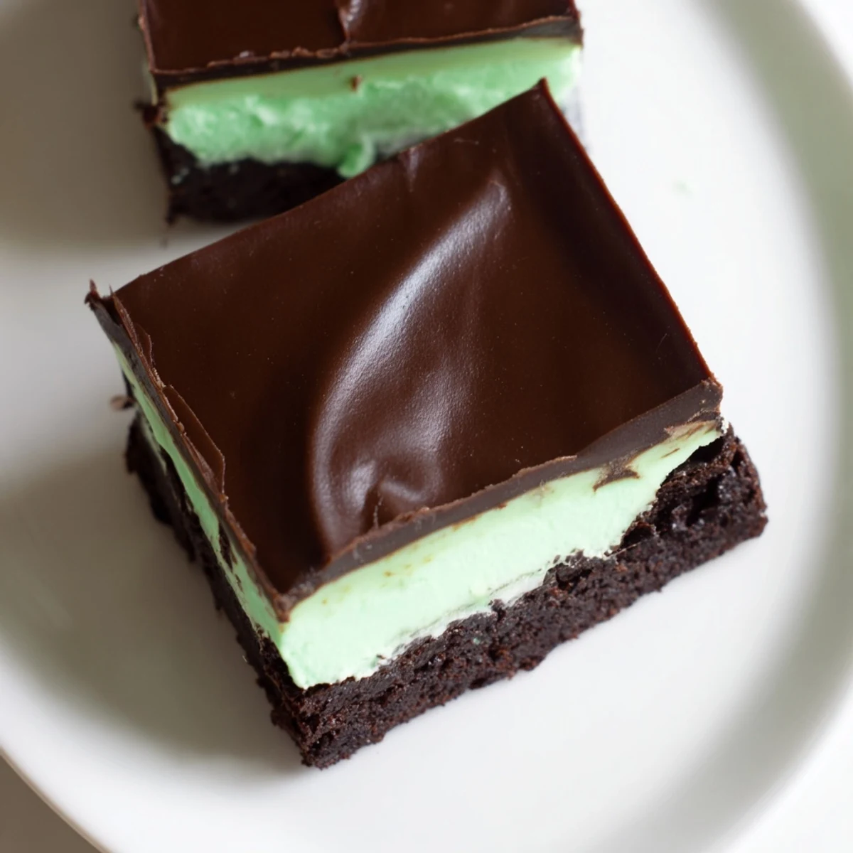 A single Shamrock Mint Brownie with Chocolate Ganache reveals minty green filling and silky ganache against a rustic background.