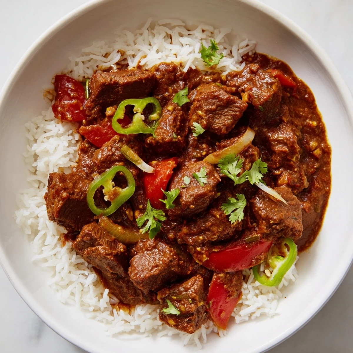 Steaming plate of homemade Spicy Beef Curry with Rice, garnished with fresh cilantro, showcasing the aromatic and hearty Indian-inspired main dish.  