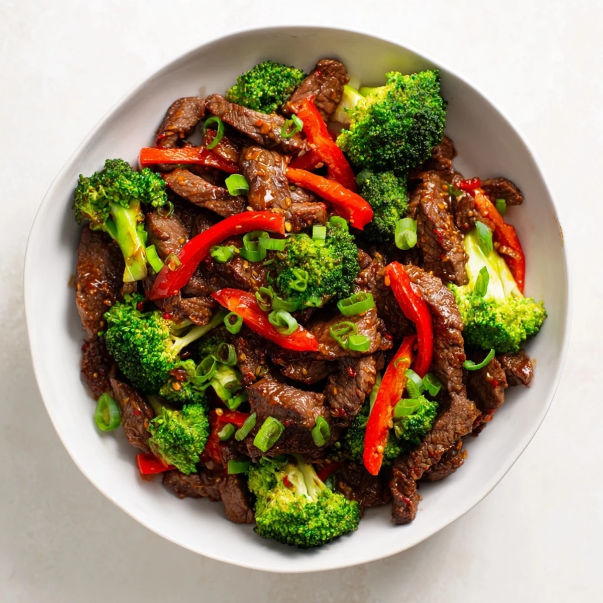 A close-up view of a vibrant Spicy Beef and Broccoli Stir Fry, featuring succulent meat, crunchy vegetables, and a rich, reddish-brown sauce in a dark skillet.