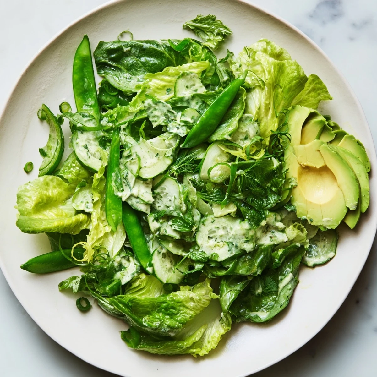 Green Salad with Green Goddess Dressing features crisp lettuce, green bell peppers, and a vibrant, herby dressing in a serving bowl.