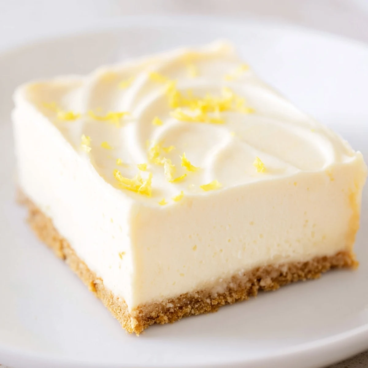 Decadent Rich Greek Yogurt Cheesecake dessert topped with a dollop of whipped cream and lemon zest.