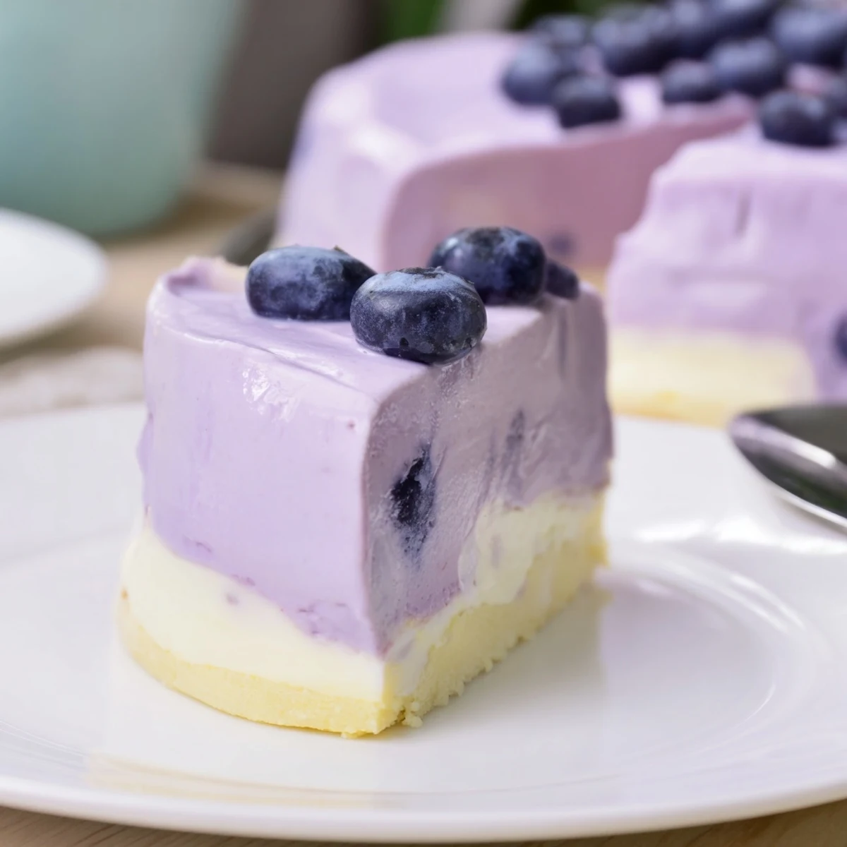 Blueberry Mousse Cheesecake is plated with a graham cracker crust and mint leaves for a summer dessert.