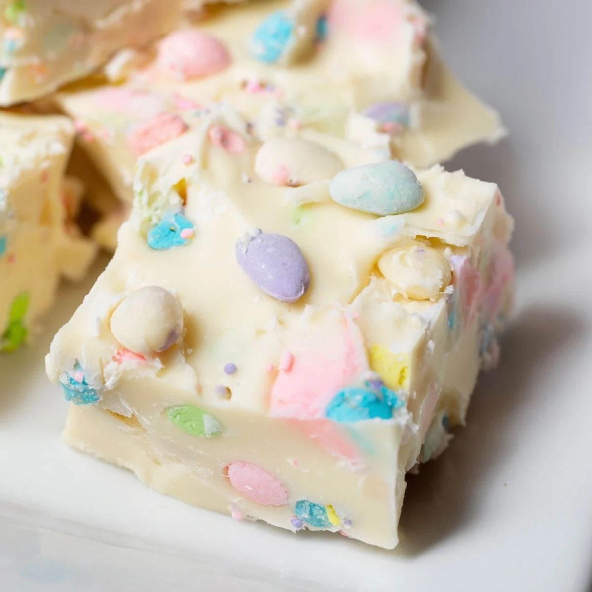 Soft Easter Fudge squares topped with colorful candy-coated eggs and sprinkles, ready to serve at a festive gathering.
