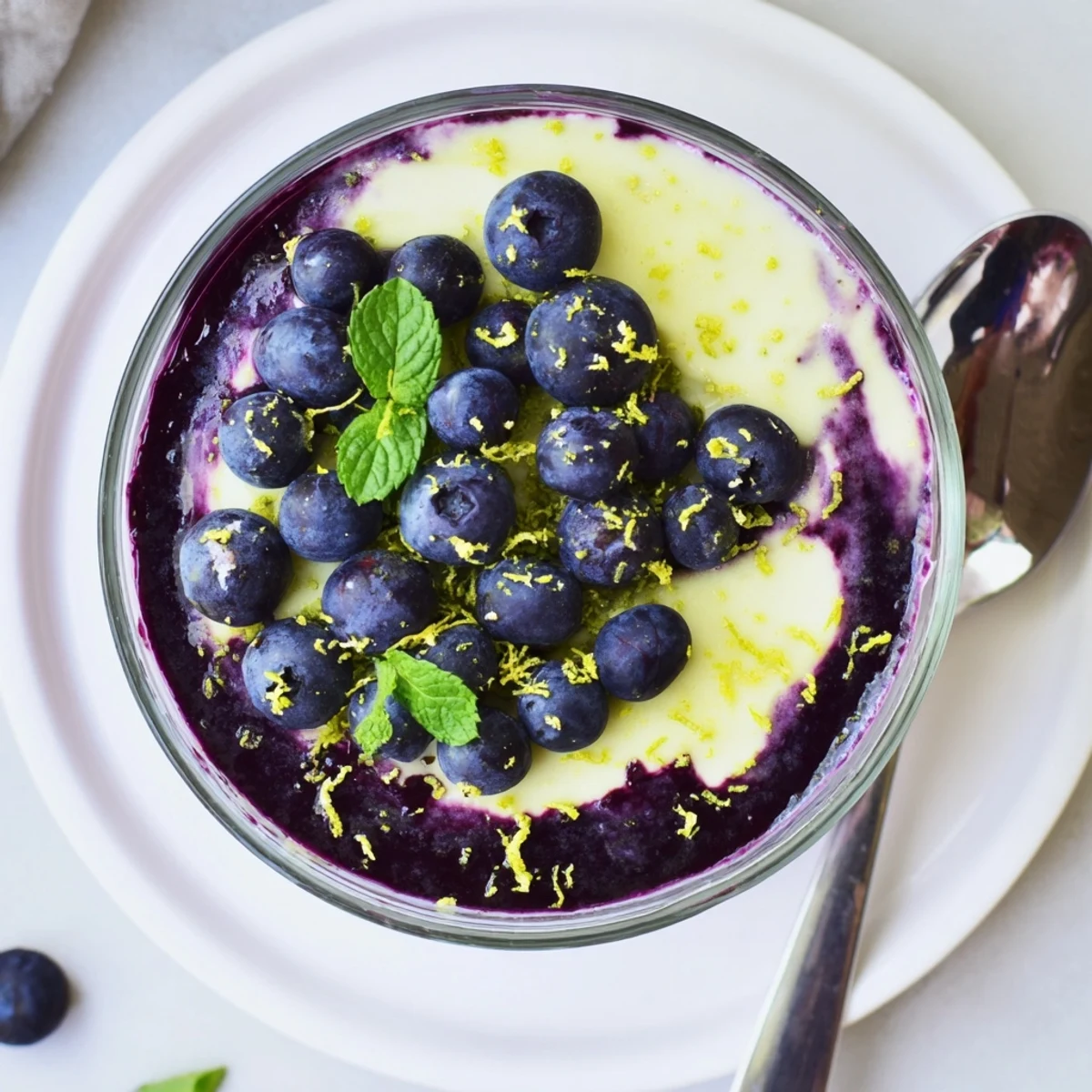 A glass of Lemon Blueberry Mousse shows a spoonful lifted from fluffy lemon mousse and jewel-toned blueberry sauce.