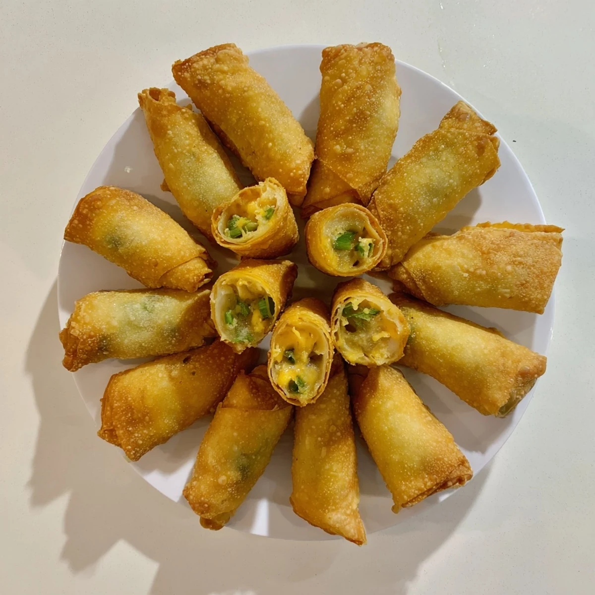 Golden-brown Mini Jalapeño Popper Egg Rolls arranged on a platter, with creamy filling visible and a side of ranch for dipping.
