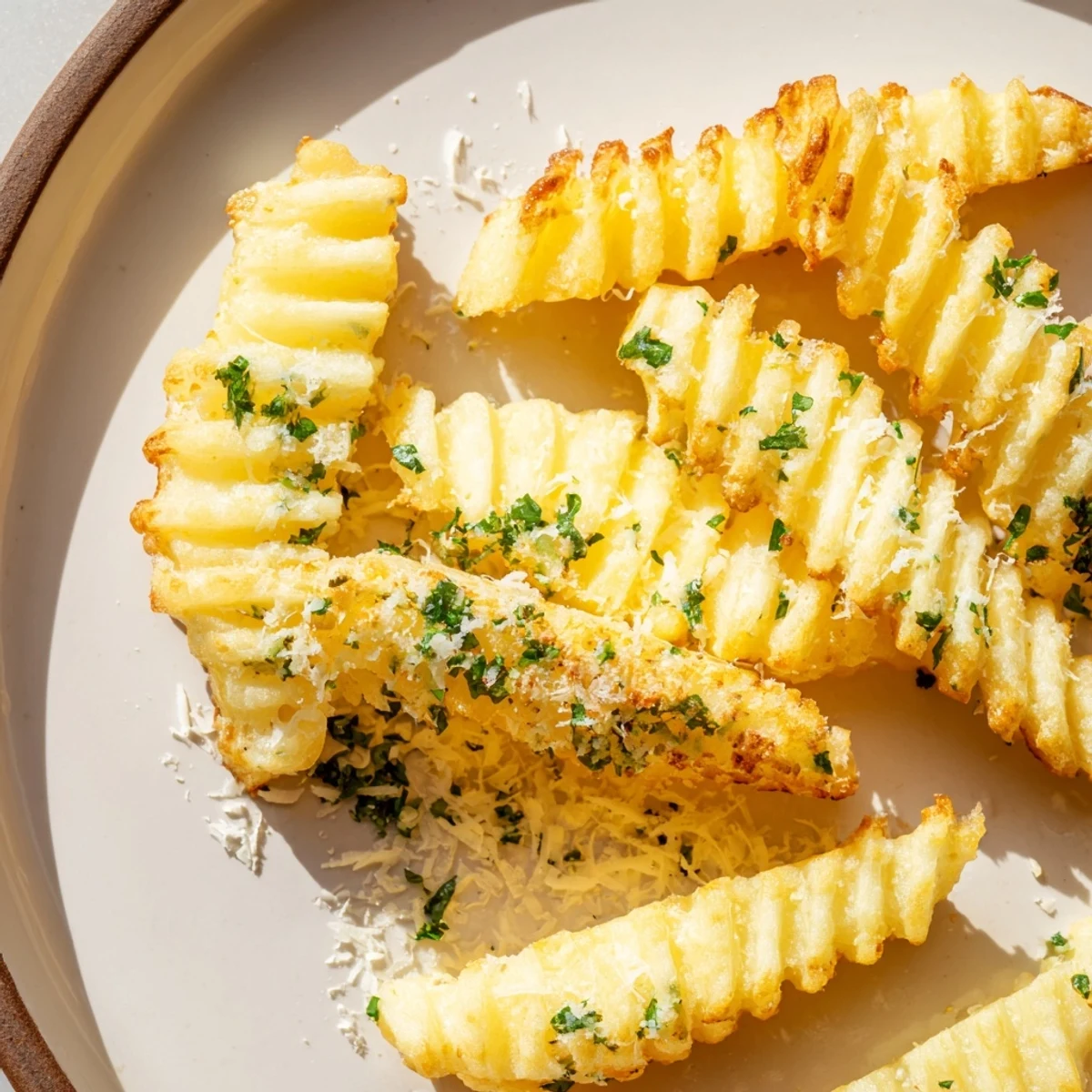A close-up of baked Crispy Mashed Potato Fries garnished with fresh parsley and grated Parmesan cheese.