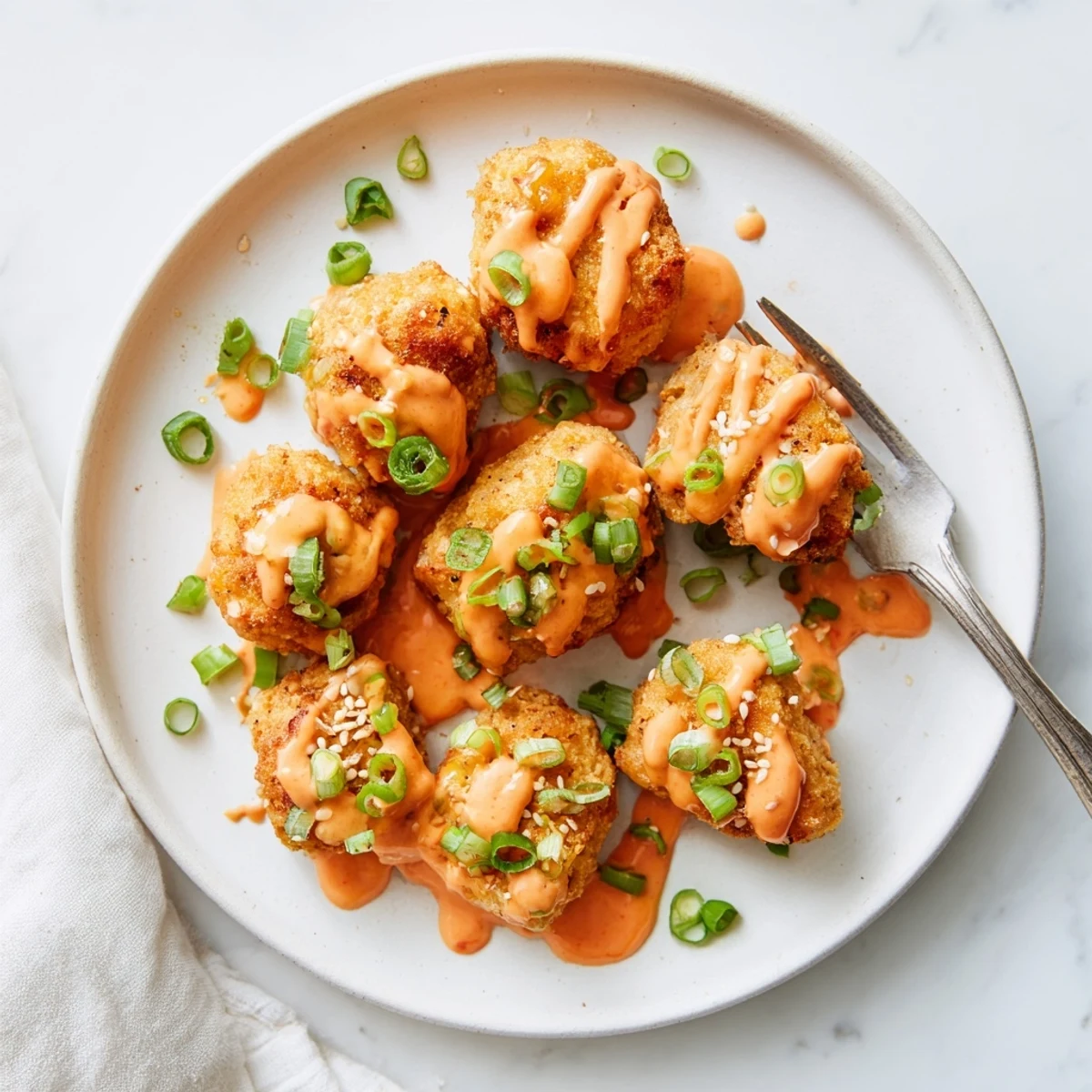 Golden-brown Quick Low Carb Bang Bang Chicken pieces coated in almond flour and parmesan, tossed in creamy spicy sauce on a platter with scallions.