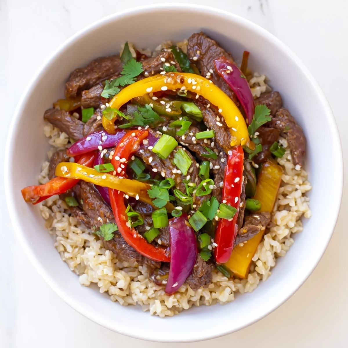 Vibrant Asian-inspired healthy beef and pepper rice bowl garnished with fresh cilantro and toasted sesame seeds