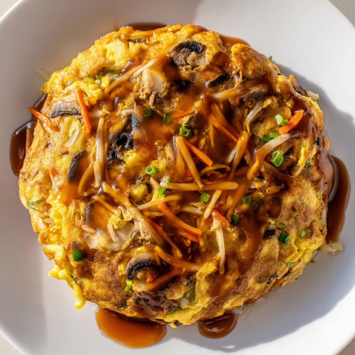 Fluffy vegetable-packed Egg Foo Young omelet fried until golden and drizzled with thick sauce