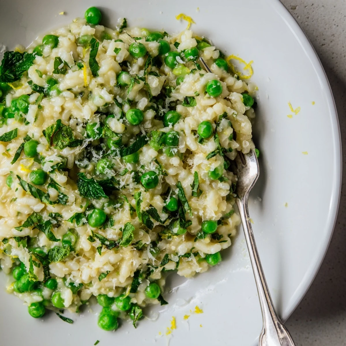 Vibrant green peas scattered throughout golden Arborio rice finished with butter and lemon zest garnish