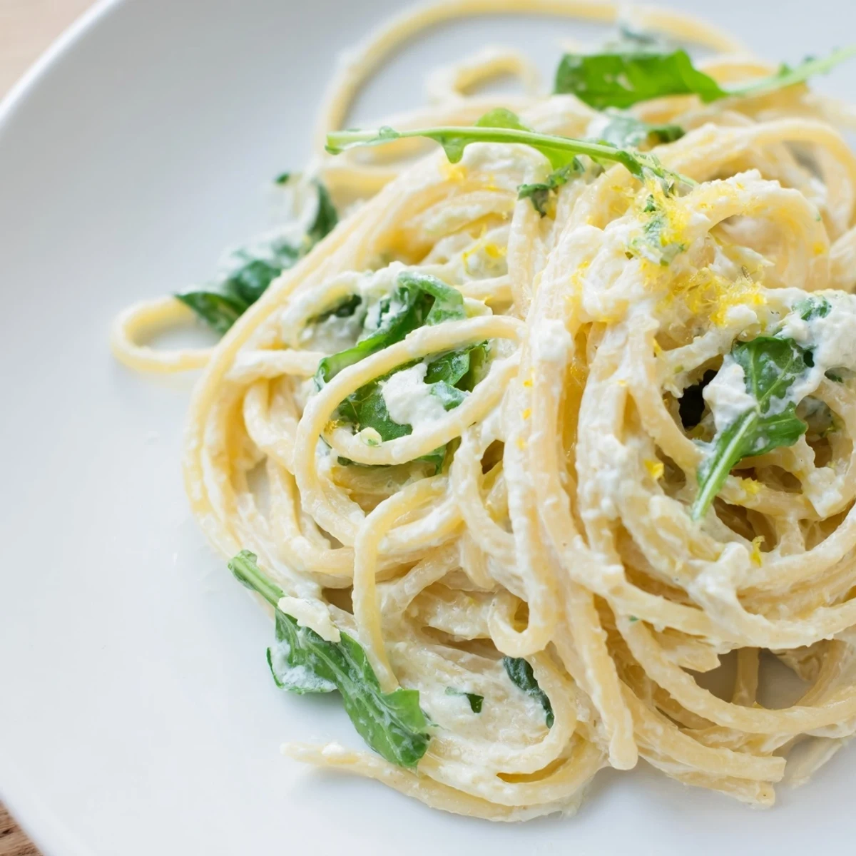 Creamy lemon ricotta pasta with fresh arugula tossed in a bright white bowl