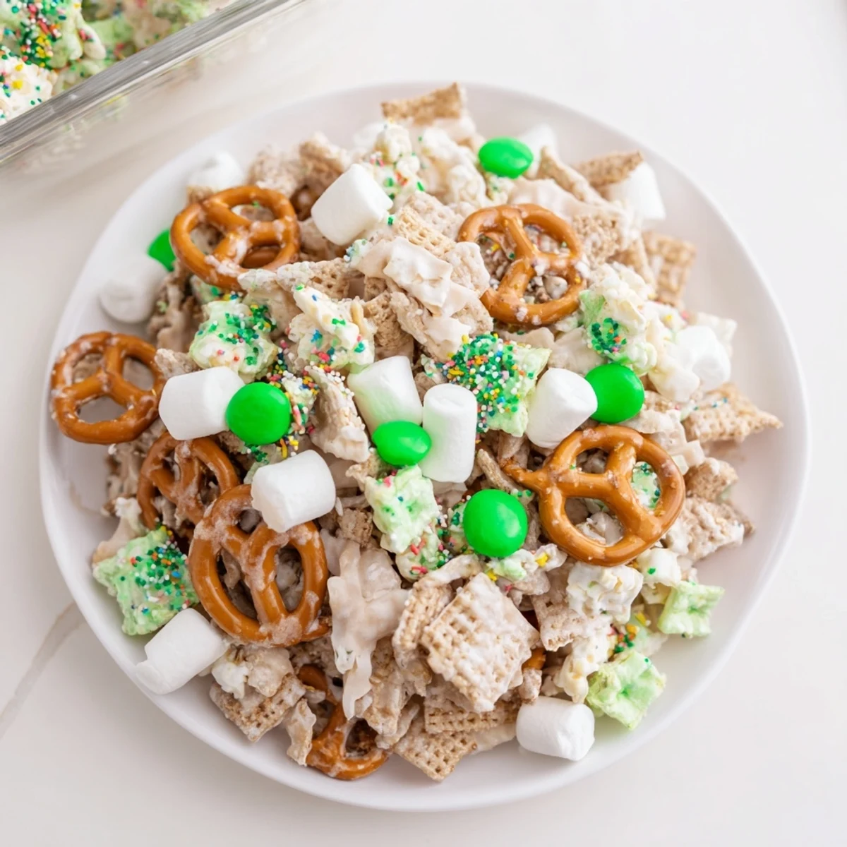Colorful Leprechaun Bait snack mix with white chocolate drizzle and rainbow sprinkles on a wooden board