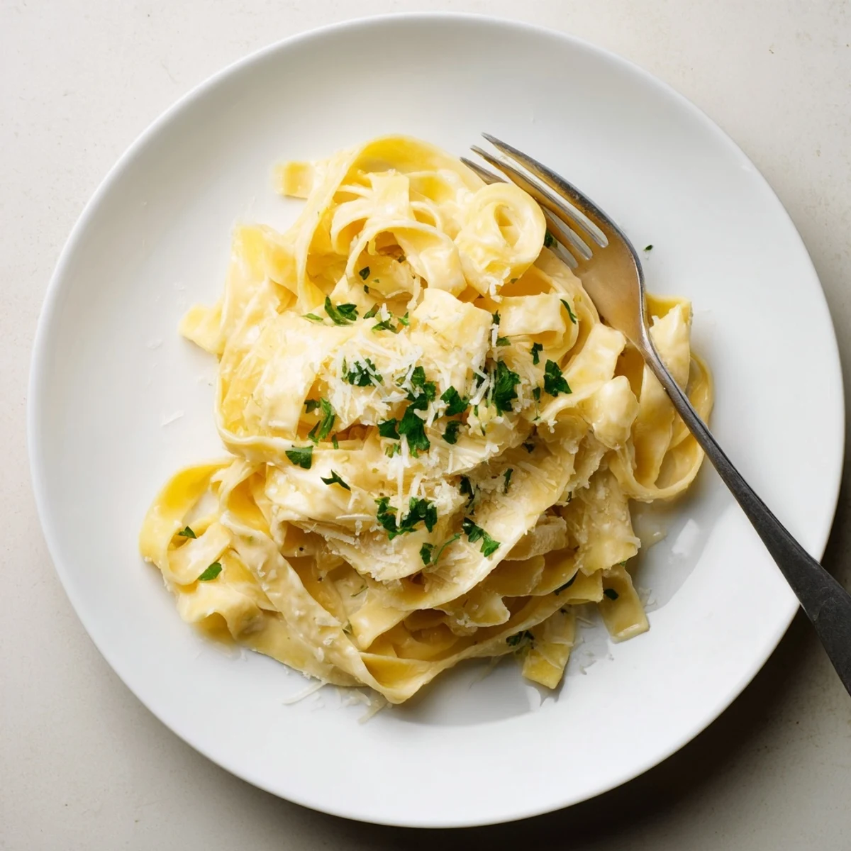 Golden fettuccine noodles coated in rich Parmesan Alfredo sauce garnished with fresh parsley