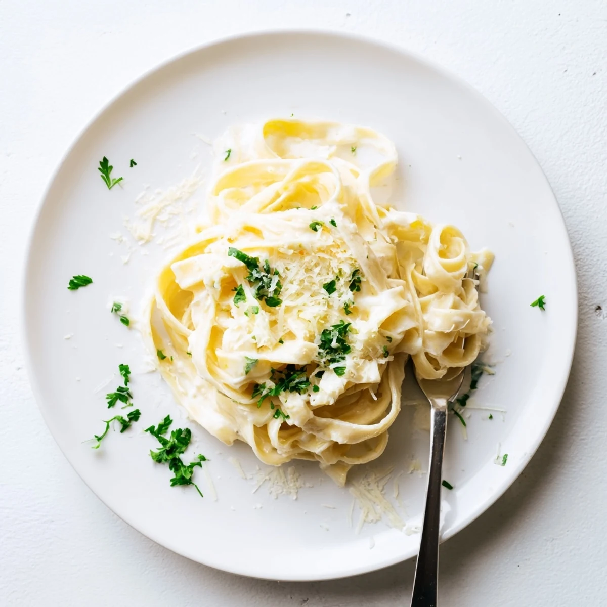 Creamy fettuccine Alfredo pasta twirled on a white plate with buttery Parmesan coating