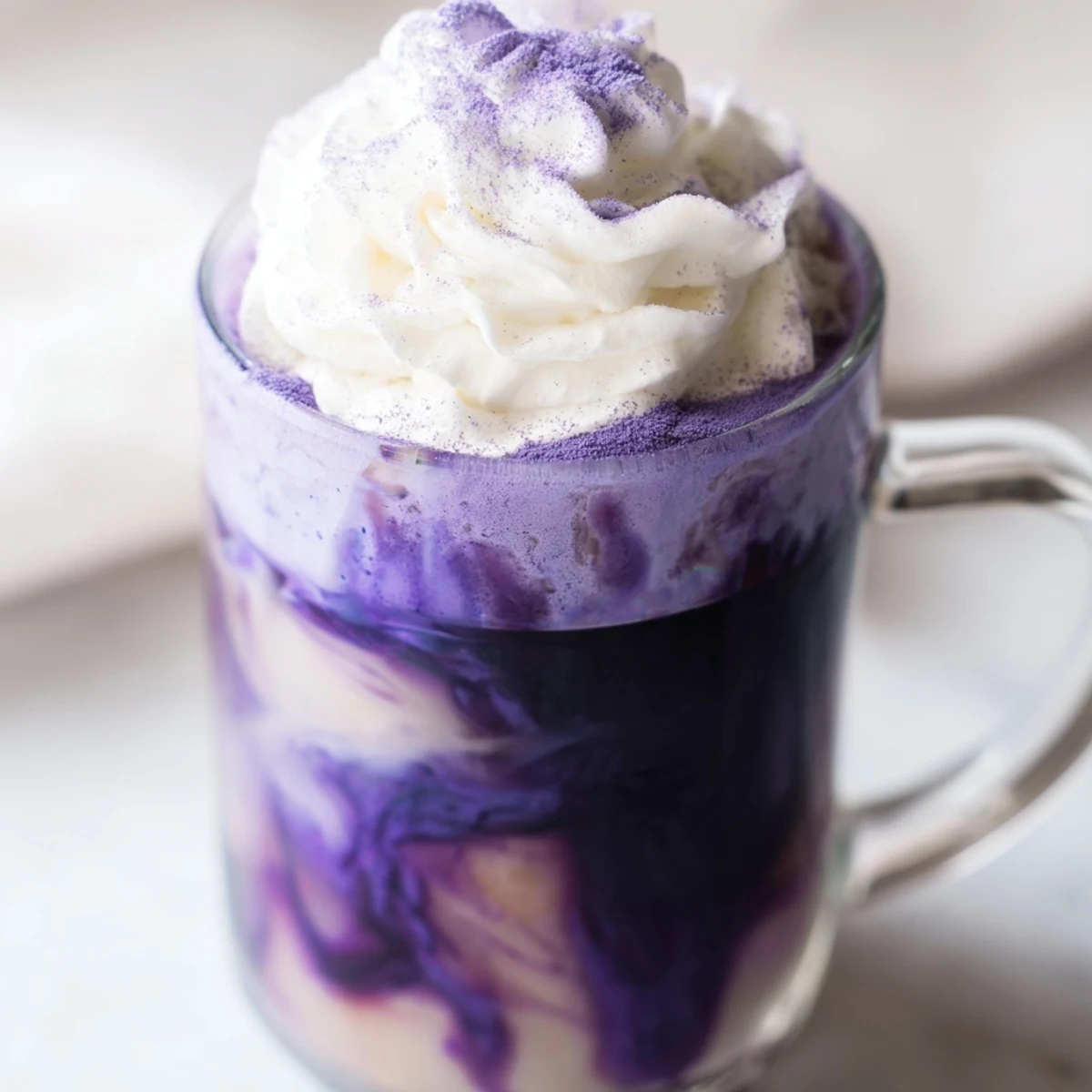 Hot Filipino ube latte with frothy milk and garnish of white cream