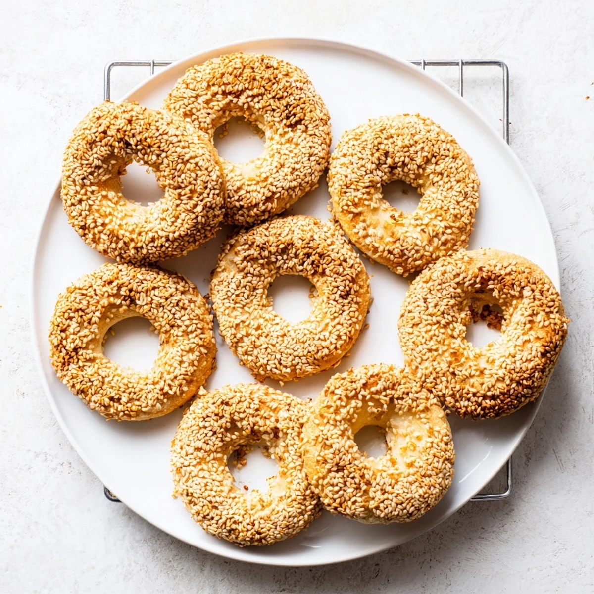 Homemade sesame bread rings coated in toasted seeds, arranged on parchment paper ready for Mediterranean snacking or breakfast
