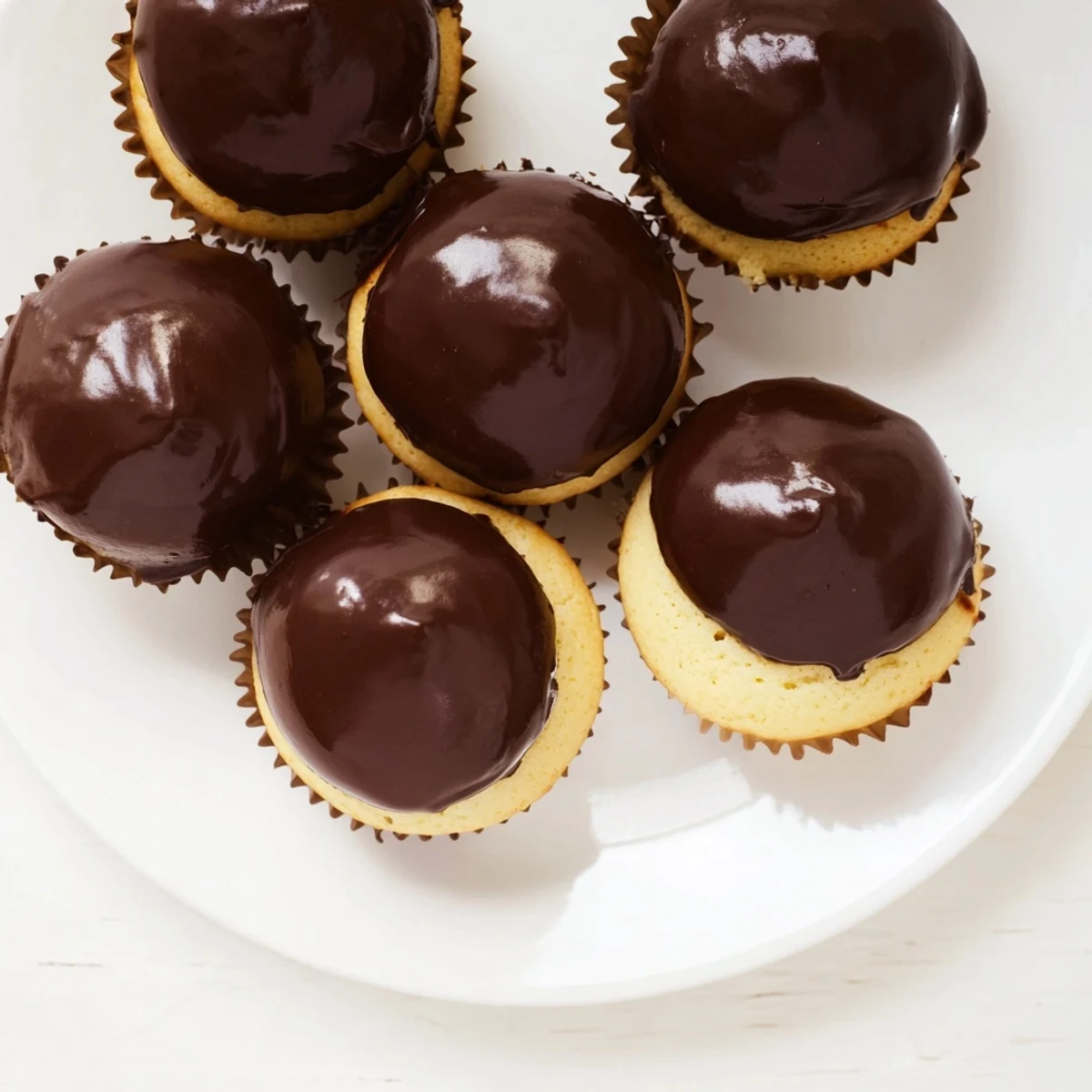 Homemade Boston cream pie cupcakes featuring rich chocolate glaze over moist vanilla cake with custard center