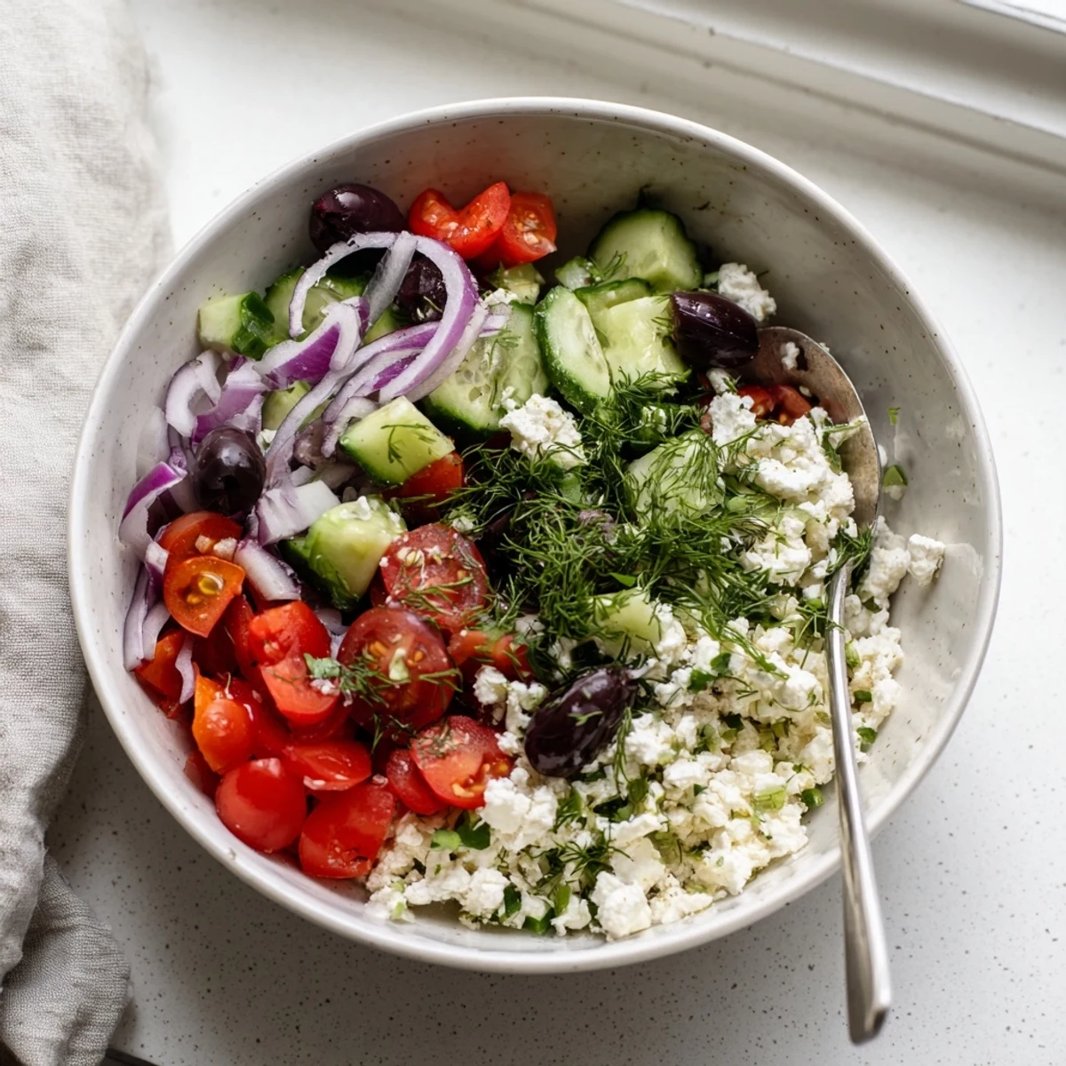 Greek salad cottage cheese bowl with cherry tomatoes, cucumber, olives, and crumbled feta cheese