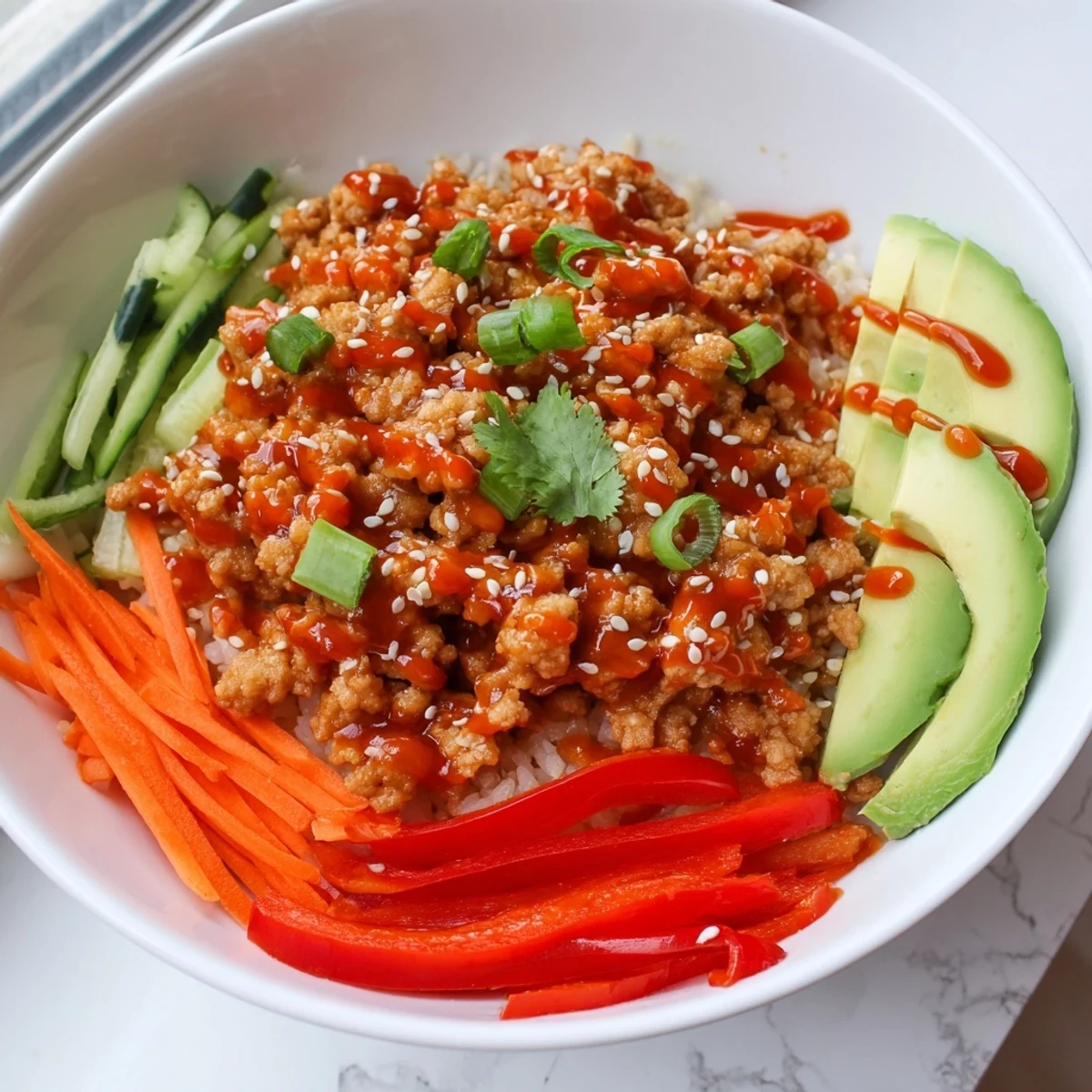 Colorful firecracker ground chicken bowls featuring zesty sauce fresh cucumber and carrots