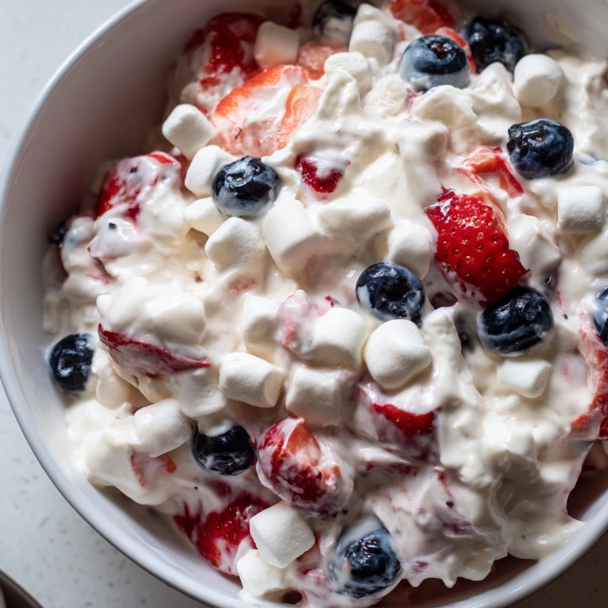 Luscious red white blue cheesecake salad piled high with marshmallows and juicy summer berries