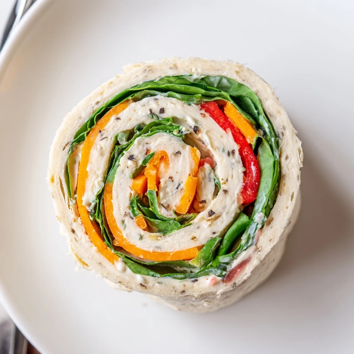 Party-style Pinwheel Sandwiches stacked on tray, cheddar, spinach, and carrot ribbons