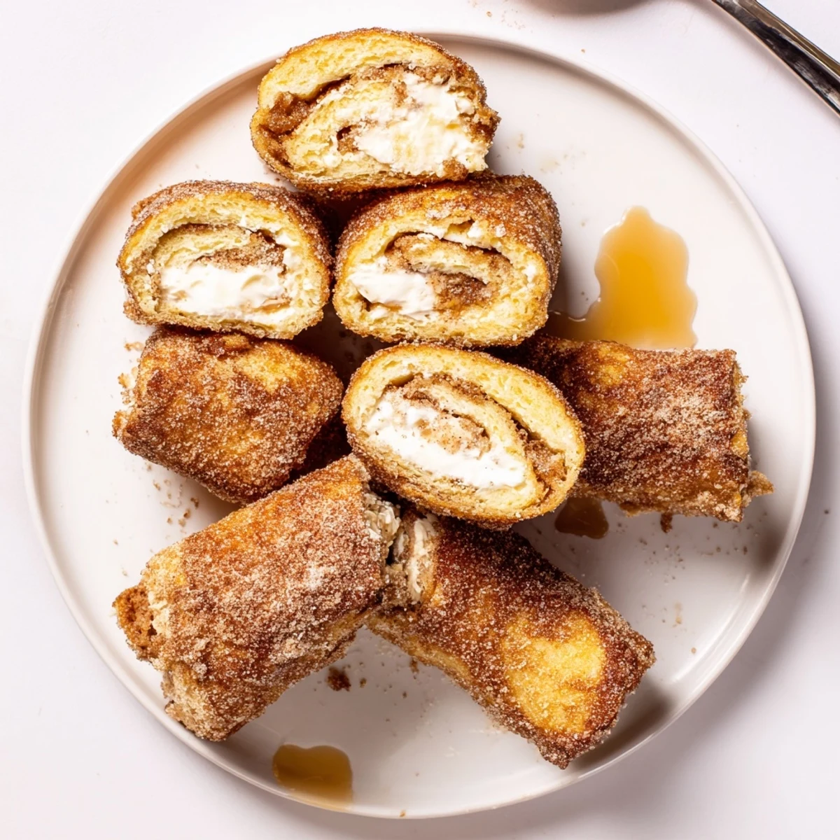 Skillet-browned Cinnamon Roll French Toast Roll Ups served with maple syrup drizzle