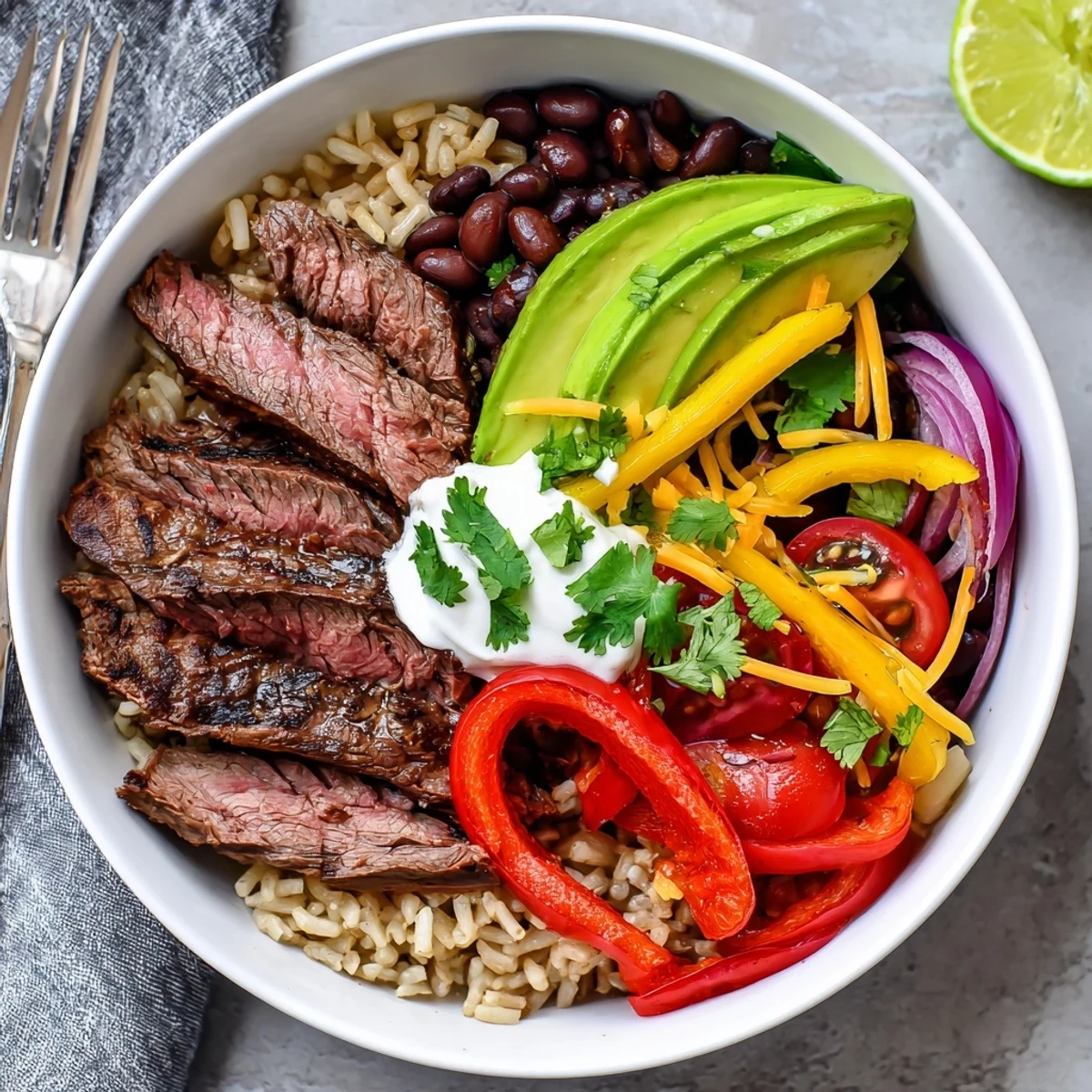 Warm Steak Fajita Power Bowls plated with creamy avocado, cilantro, and lime