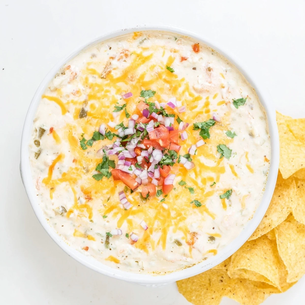 Golden green chile queso dip with roasted peppers and diced tomato ready for dipping