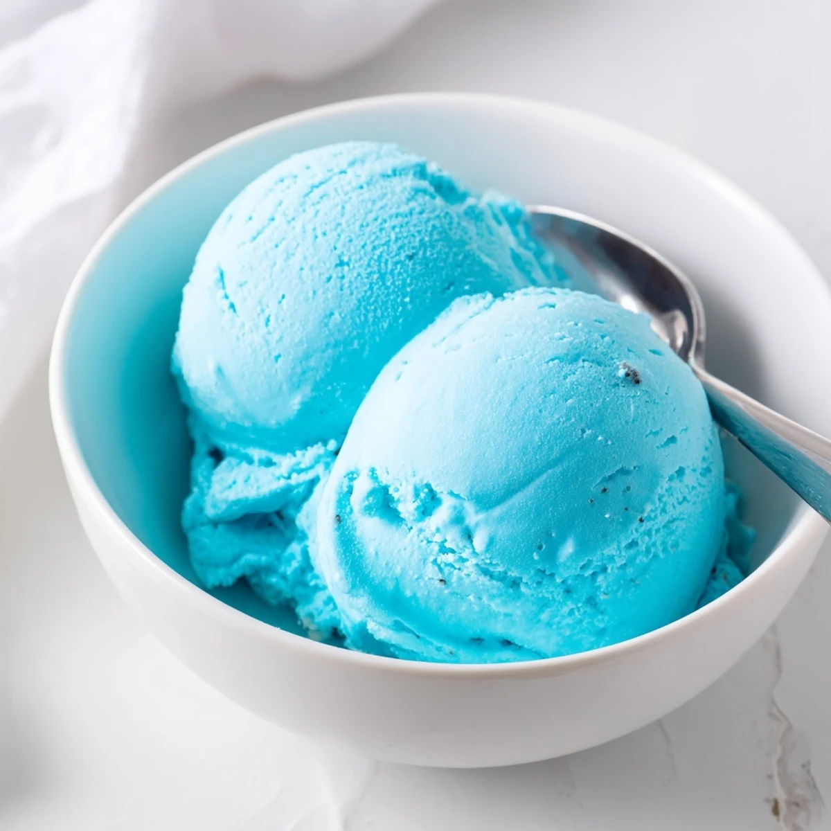 Vibrant blue moon ice cream served in a bowl topped with whipped cream