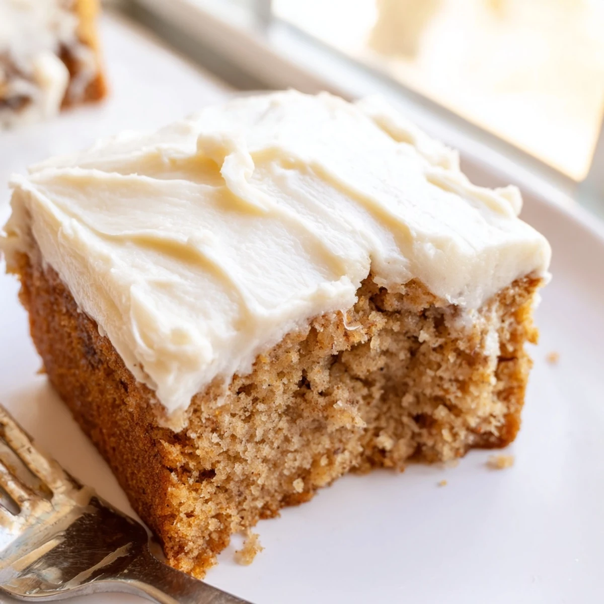 Warm brown butter banana cake topped with pillowy cream cheese frosting served on a wooden board