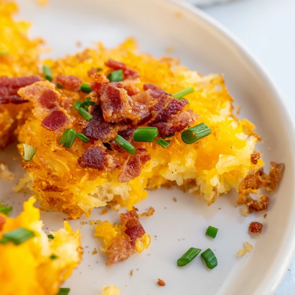 Golden brown Cheesy Loaded Hashbrown Bites served warm with sour cream and fresh chives