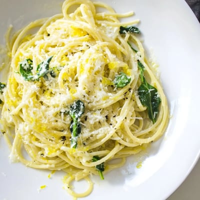Twirled spaghetti coated in tangy lemon ricotta sauce topped with peppery green arugula
