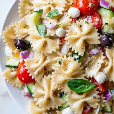 Vibrant farfalle pasta tossed with cherry tomatoes, cucumber, and tangy Italian dressing for summer picnics