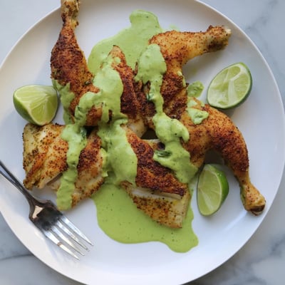 Spatchcocked Peruvian roast chicken plated alongside creamy zesty aji verde for dipping