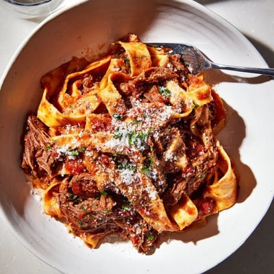 Hearty slow cooked lamb ragu with pappardelle tossed with shredded meat and fresh grated Parmigiano-Reggiano cheese