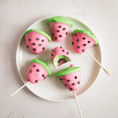 Summer dessert featuring watermelon cake pops on lollipop sticks with mini chocolate chip seeds
