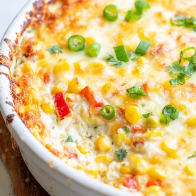 Creamy baked corn jalapeño dip topped with melted cheddar and fresh cilantro in a casserole dish