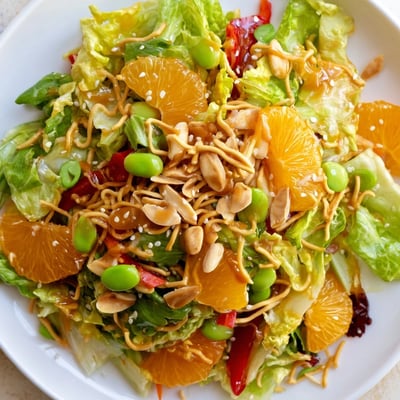 Colorful Mandarin Sesame Crunch Salad drizzled with glossy sesame ginger dressing on fresh greens