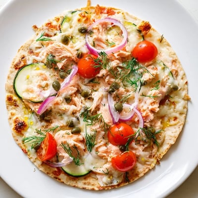 Golden tortilla base layered with flaked salmon, red onions, and bubbling mozzarella cheese